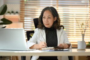 Focused middle aged woman entrepreneur reading online information on laptop.